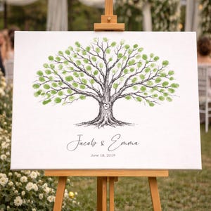 May include: A white canvas with a tree illustration, used as a guest book. The tree has green fingerprint leaves and a heart carved into the trunk. The names "Jacob & Emma" and the date "June 18, 2019" are written below the tree.