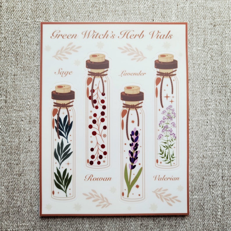 Może przedstawiać: Zestaw czterech naklejek przedstawiających szklane fiolki z r&oacute;żnymi ziołami w środku. Fiolki są oznaczone jako "Sage", "Rowan", "Lavender" i "Valerian". Naklejki są częścią kolekcji o nazwie "Green Witch's Herb Vials".