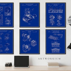 May include: A set of six blue and white patent prints featuring technical diagrams of computer hardware components, including a hard drive, mouse, keyboard, and cooling systems, displayed in black frames on a wall above a desk.