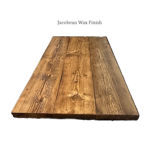May include: A rectangular wooden tabletop or board featuring a dark brown Jacobean wax finish. The surface displays a prominent natural wood grain pattern, visible knots, and textured vertical lines across three joined planks of wood.