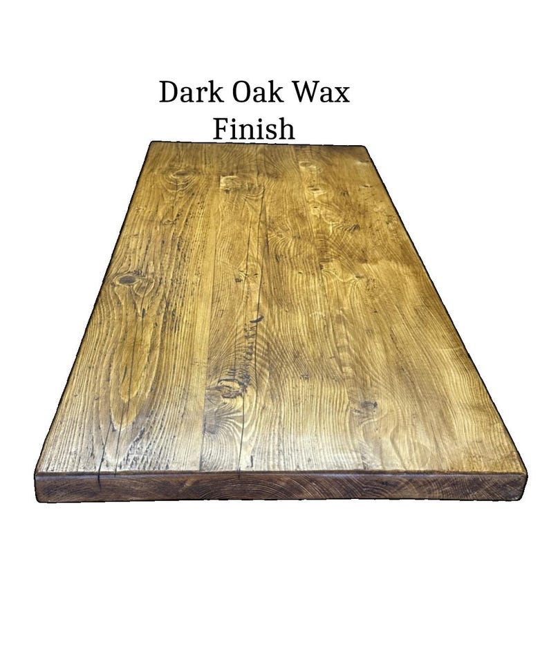 May include: A rectangular wooden tabletop featuring a dark oak wax finish. The surface displays a prominent natural wood grain pattern with visible knots and variations in the brown wood tones. The text "Dark Oak Wax Finish" is centered above.