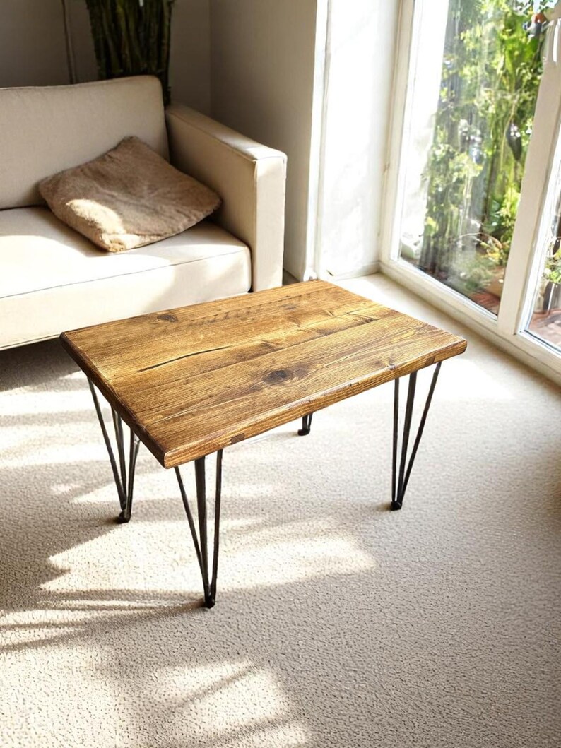 May include: A rectangular coffee table with a rustic, reclaimed wood top and black hairpin legs. The table is approximately 30 inches long, 20 inches wide, and 16 inches high. The wood has a natural, warm brown color with visible grain and knots.