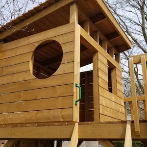 May include: A wooden playhouse with a roof, a window, and a door. The playhouse is made of natural wood and has a green door handle.
