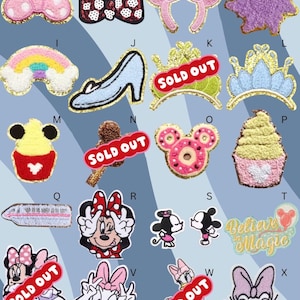 May include: A selection of embroidered patches with diverse designs. Includes Mickey Mouse and Minnie Mouse heads, bows, a castle, a rainbow, a high heel, a crown, a cupcake, a train, and Daisy Duck. Patches are in various colours with gold trim.