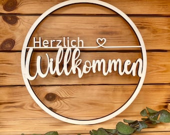 May include: A wooden circle with the words "Herzlich Willkommen" and a small heart symbol.