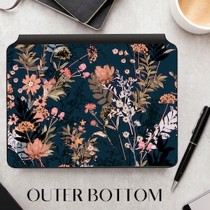Peut inclure: Une peau d'ordinateur portable bleu foncé avec un motif floral composé de fleurs roses, blanches et brunes. La peau a une bordure noire et le texte "OUTER BOTTOM" est imprimé sous l'image.
