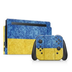 May include: A gaming console and controller skin set featuring a blue and yellow textured design. The console and controller have a flag-like appearance, with a blue upper section and a yellow lower section.