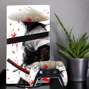 Könnte beinhalten: Eine weiße und rote PlayStation 5 Konsolenhaut mit einem Samurai-Krieger mit traditionellem japanischem Hut. Die Haut hat ein schwarz-weißes Design mit roten Akzenten. Die Konsolenhaut wird mit einer passenden Controller-Haut gezeigt.