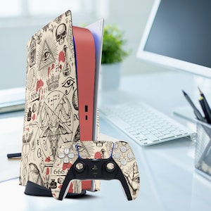 Peut inclure: Une console de jeu beige et rouge avec une manette assortie. La console et la manette sont recouvertes d'un motif de symboles occultes, de crânes et du chiffre 666. La manette est noire avec des boutons blancs.