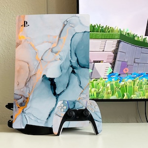 May include: A white and blue marble-patterned Playstation 5 console with a matching white and blue controller. The console has a PlayStation logo on the front.