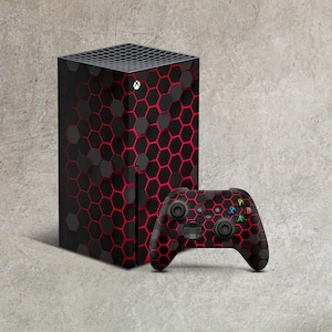 Könnte beinhalten: Eine schwarze und rote Spielekonsole mit einem Wabenmuster und einem passenden schwarzen und roten Controller.