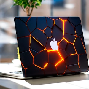 Può includere: Un computer portatile argentato con un design nero screpolato sul coperchio. Le crepe brillano di colore arancione e il logo Apple è visibile al centro del coperchio.