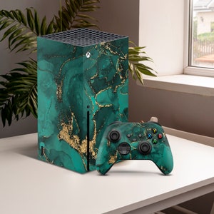 May include: A green and gold Xbox Series X console and controller with a marble pattern. The console is standing upright on a white table.