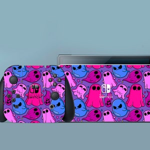 May include: A purple and pink Nintendo Switch console and controller skin with a ghost pattern. The skin features a variety of pink and blue ghosts with stars on a purple background. The text "Nintendo Switch" is printed on the console skin.