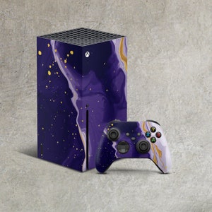 May include: A purple and gold Xbox Series X console with a matching controller. The console and controller feature a marbled design with gold flecks.