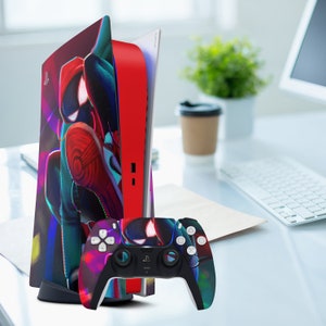 May include: A red and black video game console with a Spider-Man themed design. The console is next to a matching black and red video game controller.