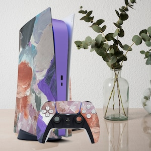 Può includere: Una console PlayStation 5 e un controller con un colorato design artistico astratto. La console ha un centro viola e il controller ha un design abbinato. L'opera d'arte presenta sfumature di viola, marrone e grigio.
