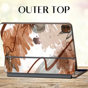 Könnte beinhalten: Eine weiße, braune und beige iPad-Hülle mit abstraktem Design. Die Hülle verfügt über eine integrierte Tastatur und einen Ausschnitt für das Kameraobjektiv. Der Text "OUTER TOP" wird über der Hülle angezeigt.