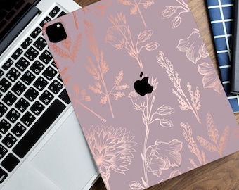 May include: A pink and rose gold iPad case with a floral pattern. The case has a white outline of flowers and leaves on a light pink background. The rose gold accents are on the flowers and leaves.