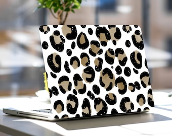 Könnte beinhalten: Ein Laptop mit einem Leopardenmuster auf dem Deckel. Der Laptop ist geschlossen und steht auf einem weißen Tisch.