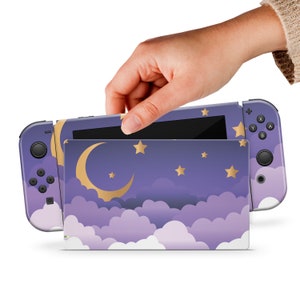Op de afbeelding: Paarse en gouden Nintendo Switch console skin met een halve maan en sterren op een bewolkte nachtelijke hemel.