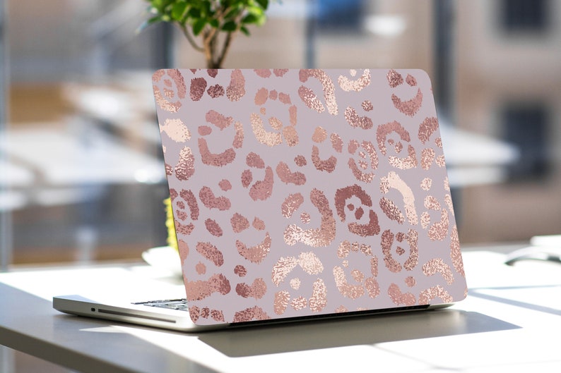 May include: A laptop computer with a decorative cover featuring a rose gold leopard print pattern on a light purple background. The laptop is open, displaying the design prominently. The design is a repeating pattern of leopard spots.
