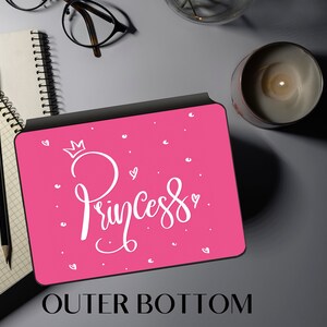 May include: A pink and black laptop case with a white crown and the word "Princess" written in cursive.