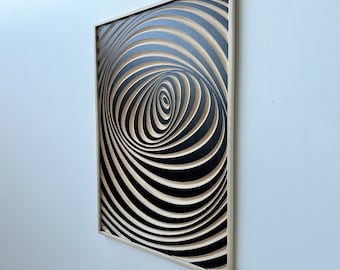 May include: A framed black and white abstract wall art piece with a swirling, hypnotic pattern. The artwork is made of wood and has a 3D effect.