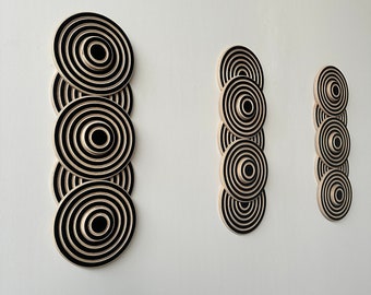 May include: Three black and white concentric circle wall decor pieces. The largest piece has five circles, the middle piece has four circles, and the smallest piece has three circles.