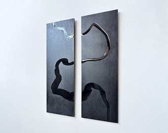 May include: Two black rectangular panels with a raised, abstract design of black and green lines. The panels are mounted on a white wall.