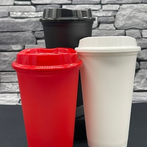 May include: Three reusable coffee cups with lids. One red cup, one black cup, and one white cup. The cups are made of a sturdy material and are designed for hot or cold drinks. The lids are designed to prevent spills.