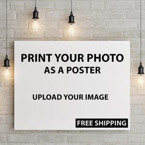 May include: A white rectangular poster with the text "PRINT YOUR PHOTO AS A POSTER" and "UPLOAD YOUR IMAGE" in black. The words "FREE SHIPPING" are in a black rectangle at the bottom. The poster is hanging on a brick wall, with several hanging light fixtures.