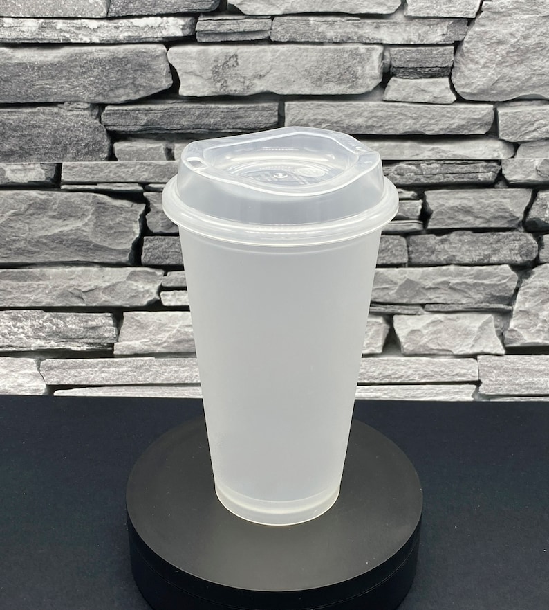 May include: A clear, frosted plastic cup with a matching lid. The cup is cylindrical with a slightly flared rim and a raised base. The lid has a drinking spout and a secure fit. The cup is designed for cold beverages.