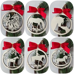 Könnte beinhalten: Sechs hölzerne Weihnachtskugeln mit Pferde-Motiv. Jede Kugel zeigt ein anderes Pferde-Design, darunter ein Pferd mit Reiter, ein Pferd mit Fohlen und ein Schaukelpferd. Die Kugeln sind weiß lackiert und haben eine rote Schleife.