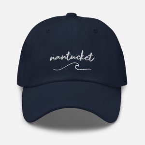 Könnte beinhalten: Eine marineblaue Baseballkappe mit weiß gesticktem Text, der "nantucket" mit einer Welle darunter sagt.