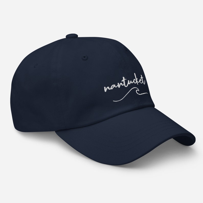May include: A navy blue baseball cap with white embroidered text that says "nantucket" with a wave underneath.