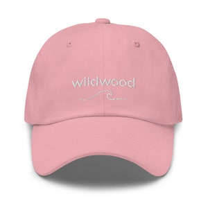 Pu&ograve; includere: Un berretto da baseball rosa con il testo "Wildwood" ricamato in bianco con un piccolo disegno di un'onda sotto.