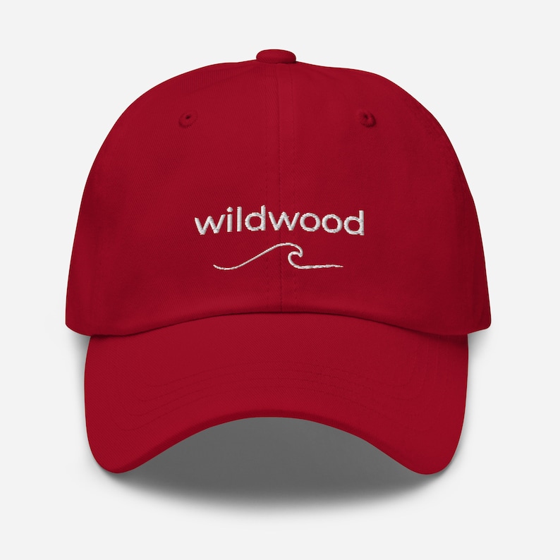 Pu&ograve; includere: Un cappello da baseball rosso con un'onda ricamata bianca e il testo "Wildwood" sul davanti.