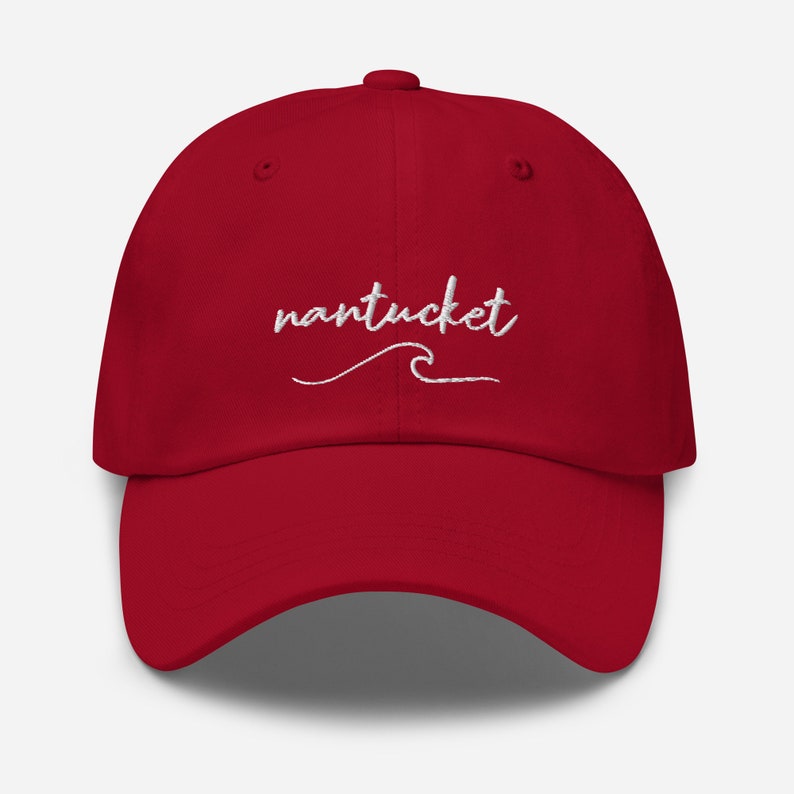 May include: A red baseball cap with white embroidered text that says "nantucket" with a wave underneath.