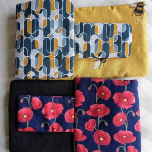 May include: A set of four fabric squares with different patterns. The top left square has a geometric pattern in shades of blue and yellow. The top right square has a solid yellow background with a geometric pattern in shades of blue and yellow. The bottom left square is black with a smaller blue square with a red floral pattern. The bottom right square has a blue background with a red floral pattern.