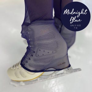 May include: A pair of midnight blue ice skate covers featuring a mesh fabric construction with reinforced panels and small decorative studs. The covers are labeled with the text Midnight Blue Girl's Size 7-8 and are worn over white ice skates.