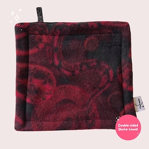 May include: Double-sided skate towel with a red and black marbled pattern. The towel has a black border and a small black tag with a letter 'Y' on it. The text 'Double-sided Skate towel' is written in white on a pink circle.