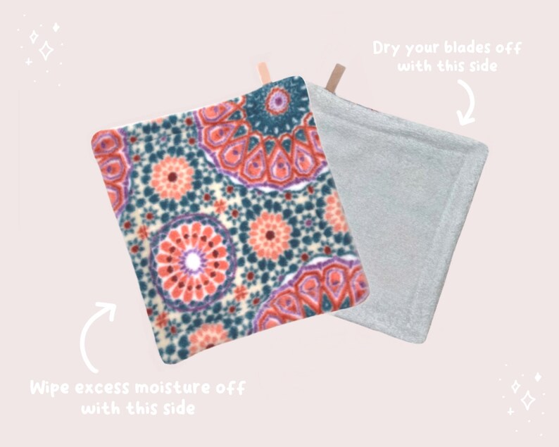 May include: A double-sided cleaning pad with a patterned side and a plain gray side. The patterned side has a colorful mandala design with shades of pink, purple, teal, and white. The text "Dry your blades off with this side" is written above the gray side and "Wipe excess moisture off with this side" is written below the patterned side.