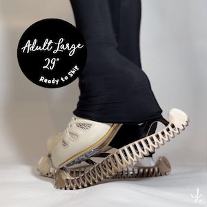 Könnte beinhalten: Cremefarbene Sportschuhe mit silbernen Verzierungen und goldenen Akzenten sind an einem beigefarbenen, federartigen Gerät befestigt. Das Bild enthält eine schwarze Hose und einen schwarzen Kreis mit dem Text "Adult Large 29" Ready to Ship."