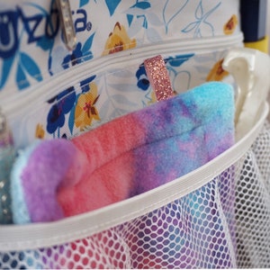 May include: A white mesh bag with a pink and blue tie-dye fabric pouch inside. The pouch has a sparkly pink zipper pull.