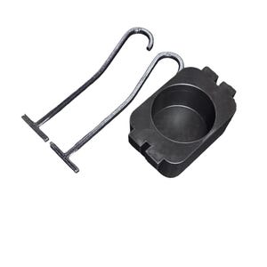 May include: A black metal branding iron with a curved handle and a rectangular base. The branding iron is next to a black, rectangular holder with a circular indentation.