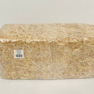 Puede incluir: Una paca rectangular de paja envuelta en pl&aacute;stico transparente. La paja es de color marr&oacute;n claro, y el envoltorio de pl&aacute;stico es transparente. Una peque&ntilde;a etiqueta blanca con texto y c&oacute;digo de barras es visible.