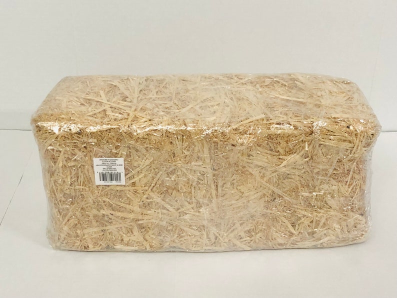 Puede incluir: Una paca rectangular de paja envuelta en pl&aacute;stico transparente. La paja es de color marr&oacute;n claro, y el envoltorio de pl&aacute;stico es transparente. Una peque&ntilde;a etiqueta blanca con texto y c&oacute;digo de barras es visible.
