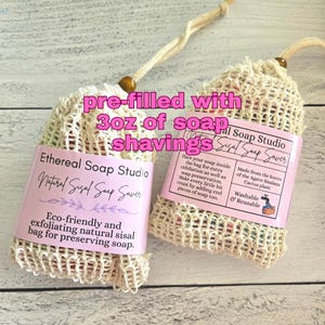 May include: Two beige sisal mesh soap saver bags with drawstring closures and wooden beads, each pre-filled with 3oz of soap shavings. The bags feature pink paper labels with black text reading Ethereal Soap Studio and Natural Sisal Soap Saver.
