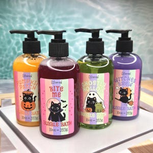 May include: Four clear plastic bottles with black pump dispensers containing bubble bath in orange, dark purple, green, and light purple. Each bottle features a label with a black cat illustration and the text Pumpkin Patch, Bite Me, Ghostly Hollow, or Witches Brew, with 10oz - 283g printed on each.